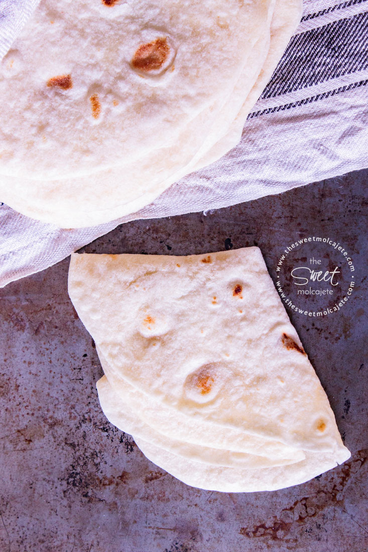 Vista de arriba aun apilo de tortillas y una de ellas esta doblada en cuartos para mostrar lo suave que es