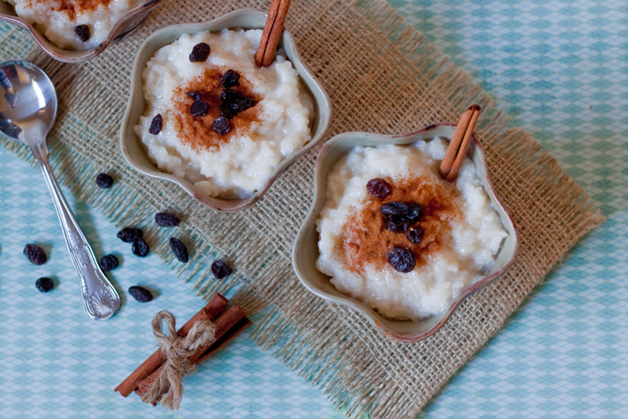 Vista de arriba a tres tazones con arroz con leche con pasitas y canela