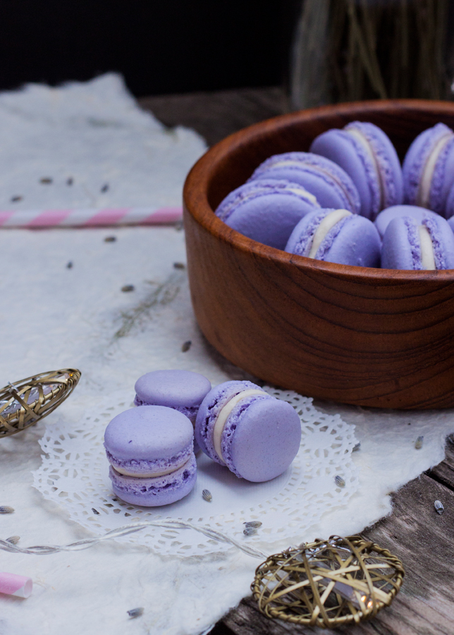 Acercamiento a 3 mini french macarons, al fondo un plato de madera con macarons de tamaño normal