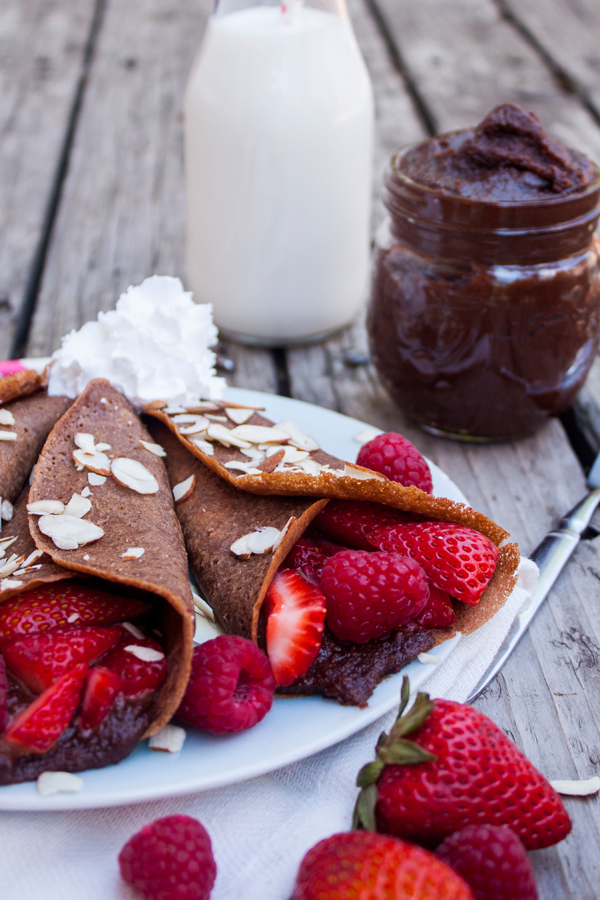 acercamiento al relleno de dos crepas de chocolate, el relleno es crema de avellanas con fresas y frambuesas