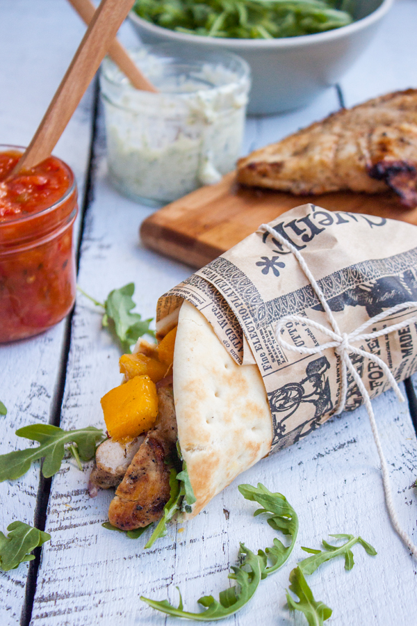 Gyro de pollo con hojitas de arúgula y mango picado, al fondo salsa tzatziki y salsa la victoria