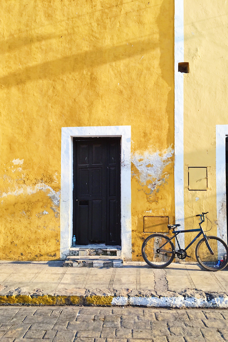 Bicicleta recargada en las paredes amarillas de Izamal, Yucatán