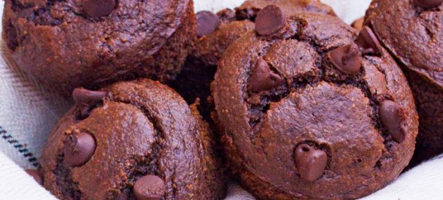 Acercamiento a varios muffins de chocolate sin gluten acomodados en un molde para pan de metal cubierto con tela de lino