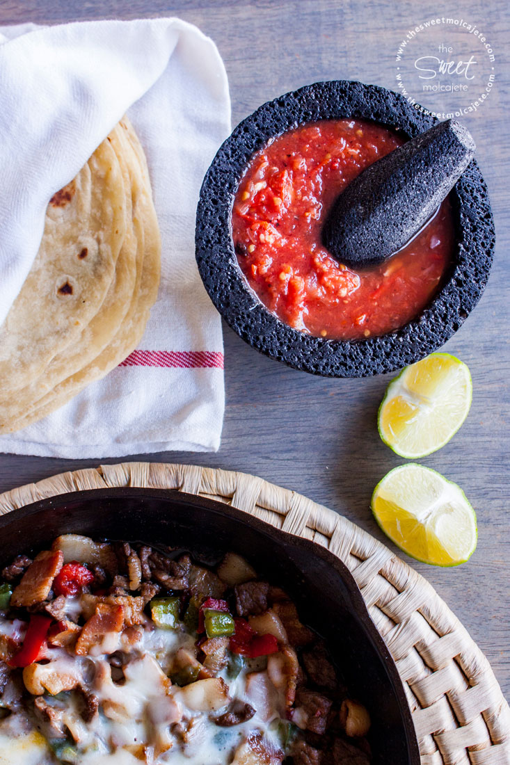 Vista aérea de un molcajete con Salsa Roja con Habanero, tortillas de harina y un sartén con alambre mexicano