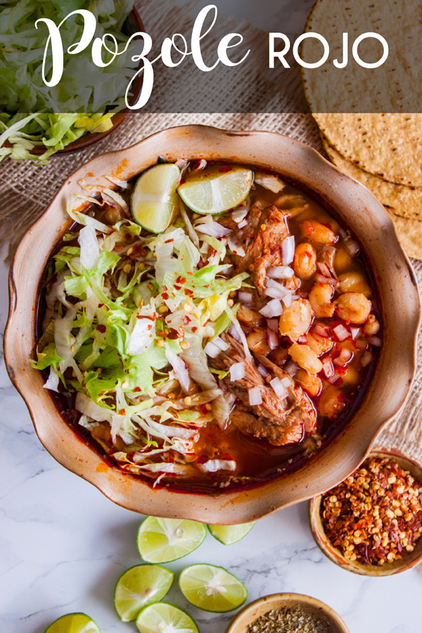 Vista aérea de un plato de pozole rojo con carne de cerdo con lechuga y otros condimentos con texto que dice pozole rojo