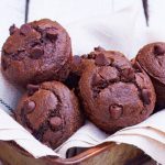 Acercamiento a varios muffins de chocolate sin gluten acomodados en un molde para pan de metal cubierto con tela de lino