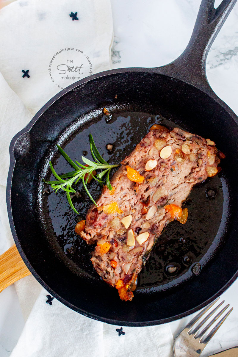 rebanada de relleno para pavo de carne de cerdo en un sarten de hierro, con una ramita de romero a un lado